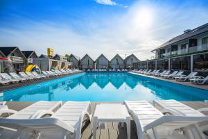 a large swimming pool with lounge chairs at Holiday Park & Resort Grzybowo in Grzybowo