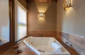 Hotel Canto Verde في غرامادو: حوض استحمام كبير في حمام مع نافذة