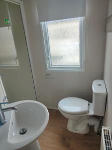a bathroom with a toilet and a sink and a window at Haven Holiday Park 3 bedroom Cala Gran Fleetwood in Thornton