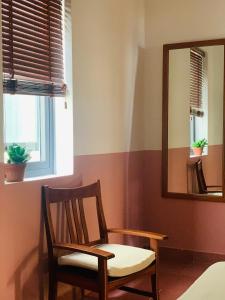 une chaise et un miroir dans la chambre dans l'établissement An Hiên Homestay Hội An, à Hội An