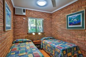 a room with two beds and a brick wall at Bayside Holiday Apartments in Broome