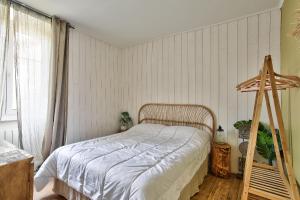 a bedroom with a bed with white sheets and a window at Charmante maison bretonne pour 6, a Saint-Suliac in Saint-Suliac