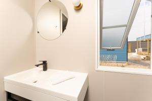 ein Bad mit einem Waschbecken, einem Spiegel und einem Fenster in der Unterkunft Boje 67 in Scharbeutz