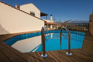 a swimming pool next to a wooden deck at Traditional Ioannis Cottage in Nerokhórion