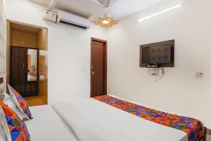 a bedroom with a bed and a tv on the wall at FabExpress Shree Karuna in Transport Nagar