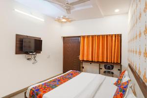 a bedroom with a bed and a tv on the wall at FabExpress Shree Karuna in Transport Nagar