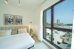 a bedroom with a white bed and a large window at Classy One Bed, Burj Al Arab View, Beach Access in Dubai