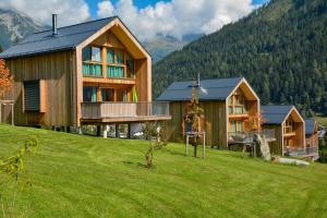a large wooden house on a hill with a green field at HOCHoben Chalets & Mobilhomes in Mallnitz