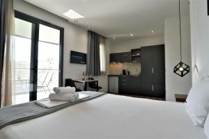 a bedroom with a large white bed and a kitchen at Feel Athens Studios at Monastiraki in Athens