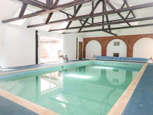 a large swimming pool with blue water in a building at Beautiful 10 Bed Oak beamed Country House in Tibenham