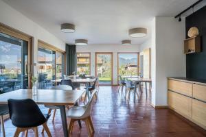 un comedor con mesas, sillas y ventanas en Pension Grasser Apartment, en Ora - Auer