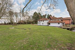 a large yard with a white house and a building at Amazing Spa Country House with Indoor Pool, Sauna and Steam Room in Tibenham