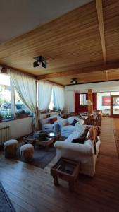 una sala de estar con sofás blancos y techo de madera. en Hosteria Posta de los Colonos en Villa La Angostura