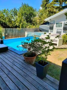a backyard deck with a swimming pool and a house at Pentz House in Siófok