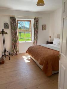 - une chambre avec un grand lit et une fenêtre dans l'établissement Newly renovated Cottage with private trout fishing set in beautiful wildlife estate, à Monaghan