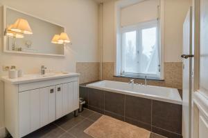 a bathroom with a tub and a sink and a window at Oceanide - Gerenoveerde luxe villa vlak bij het strand in De Haan +32 photos