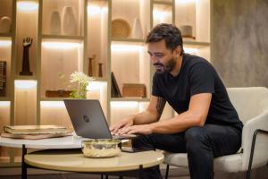 a man sitting in a chair using a laptop computer at 1253 Recoleta Small Hotel in Buenos Aires