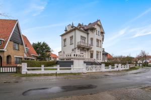 a white house with a fence in front of a street at Oceanide - Gerenoveerde luxe villa vlak bij het strand in De Haan
