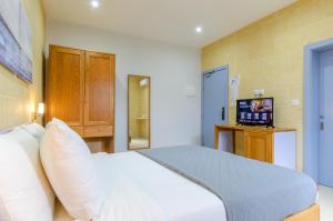 a bedroom with a white bed and a television at Country Stays Hostel in Sannat