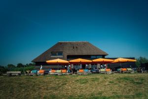 un edificio con sombrillas naranjas, mesas y sillas en Buitenplaats de Luwte en Zwolle