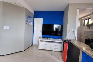 a kitchen with a blue wall and a tv at Apartamento pé na areia in São Luís