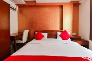 1 dormitorio con cama con almohadas rojas y escritorio en Flagship Hotel Grand Decor, en Jaipur