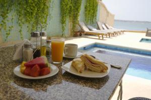 uma mesa com dois pratos de comida e um copo de sumo de laranja em Hotel Caribbean Cartagena em Cartagena de Indias