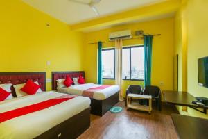 a hotel room with two beds and a desk and a television at OYO Hotel Shree Balajee 1 in Puri