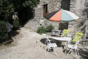 une table et des chaises avec un parasol en face d'un bâtiment dans l'établissement Meublé en Drôme Provençale, à Saint-Auban-sur-Ouvèze