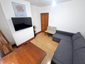 a living room with a couch and a flat screen tv at Two bedroom apartment near Lewisham Station in London