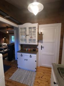 una cucina con armadietti bianchi e una porta bianca di Gaulabua - cozy cabin by the river Gaula a Haltdalen
