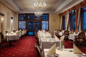 カルロヴィ・ヴァリにあるフンボルト パーク ホテル＆スパの白いテーブルと椅子、シャンデリアのあるレストラン