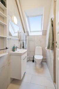 a bathroom with a toilet and a sink and a window at LOVELY TOP FLOOR Apart COPENHAGEN NEAR AIRPORT, METRO AND THE BEACH in Copenhagen