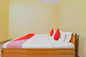 a bedroom with a bed with red and white pillows at OYO Royal Castle Near Baga Beach in Baga
