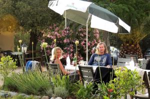 two people sitting at a table under an umbrella at Feriendorf La Mora in Calvi +28 photos
