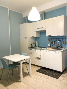 una cucina con armadi bianchi, tavolo e sedie di Dimora Anna a Termoli