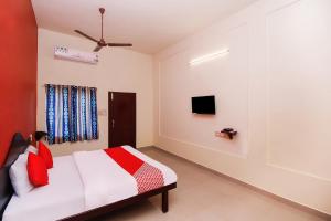 a bedroom with a bed and a tv on the wall at Hotel Aljemin in Kanyakumari
