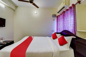 a bedroom with a large bed with red pillows at Senthamizh Residency in Chennai