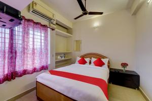 a bedroom with a large bed with red pillows at Senthamizh Residency in Chennai