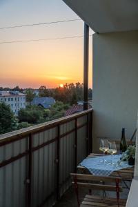 uma varanda com uma mesa com copos de vinho e o pôr-do-sol em Warm & Cozy Apartment with balcony in Valmiera em Valmiera