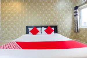 a bedroom with a large bed with red pillows at Hotel Alpine Glow Heights in Trimulgherry