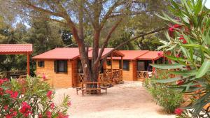 a wooden cabin with a tree and some flowers at Feriendorf La Mora in Calvi
