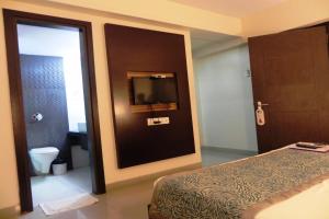 1 dormitorio con cama, TV y baño en Reeva Regency, en Shirdi