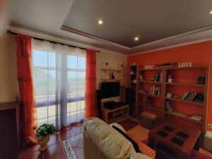 a living room with a couch and a large window at Casa Rosa - Vereda da Ilha in Santana