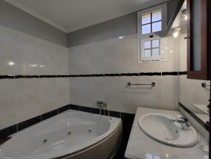 a white bathroom with a tub and a sink at Casa Rosa - Vereda da Ilha in Santana +4 photos