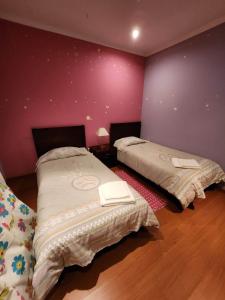 two beds in a room with purple walls at Casa Rosa - Vereda da Ilha in Santana