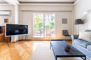 sala de estar con TV de pantalla plana grande en Spacious renovated flat in the Athens Riviera en Atenas