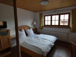 una camera da letto con un letto con lenzuola bianche e una finestra di Kitz Alm Saarwellingen a Saarwellingen