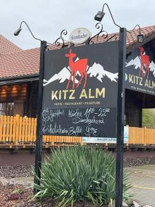 un panneau indiquant un restaurant kitziasm alim devant un bâtiment dans l'établissement Kitz Alm Saarwellingen, à Saarwellingen