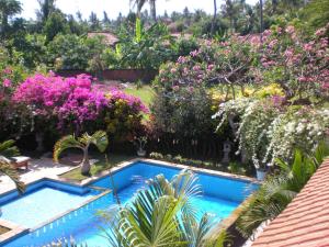 a swimming pool in a garden with pink flowers at Villa Jaya in Lovina